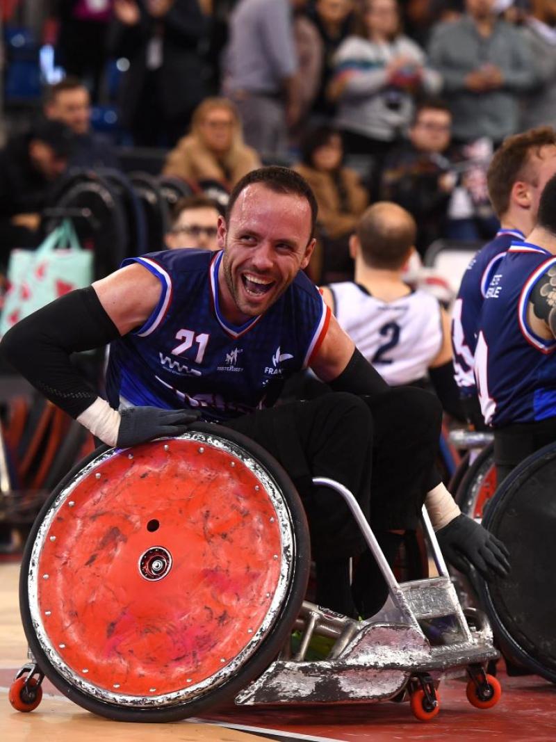 A male wheelchair rugby player smiles on the court.